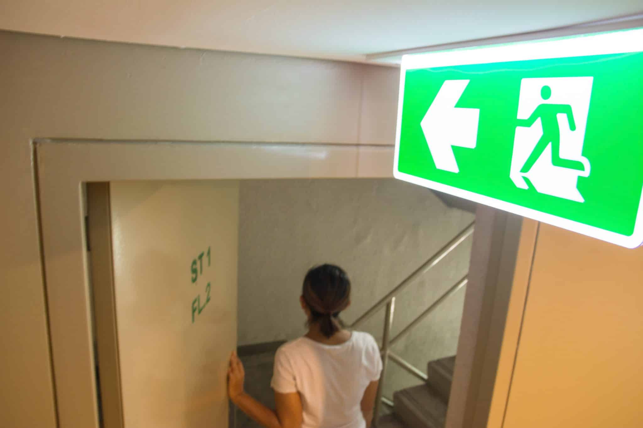 Emergency,Fire,Exit,Sign,At,The,Corridor,In,Building lady using fire exit door leading to fire exit stairway