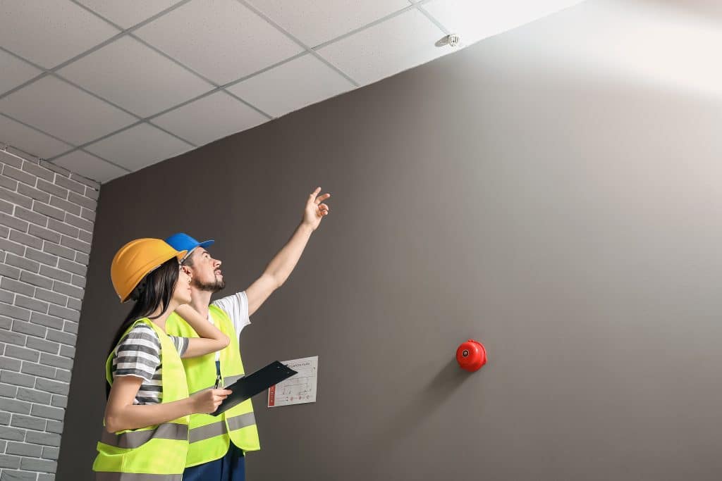 People in hi-vis pointing at fire alarm