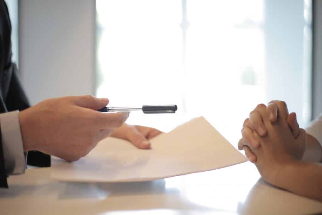 Passing a pen and a document over a table to sign